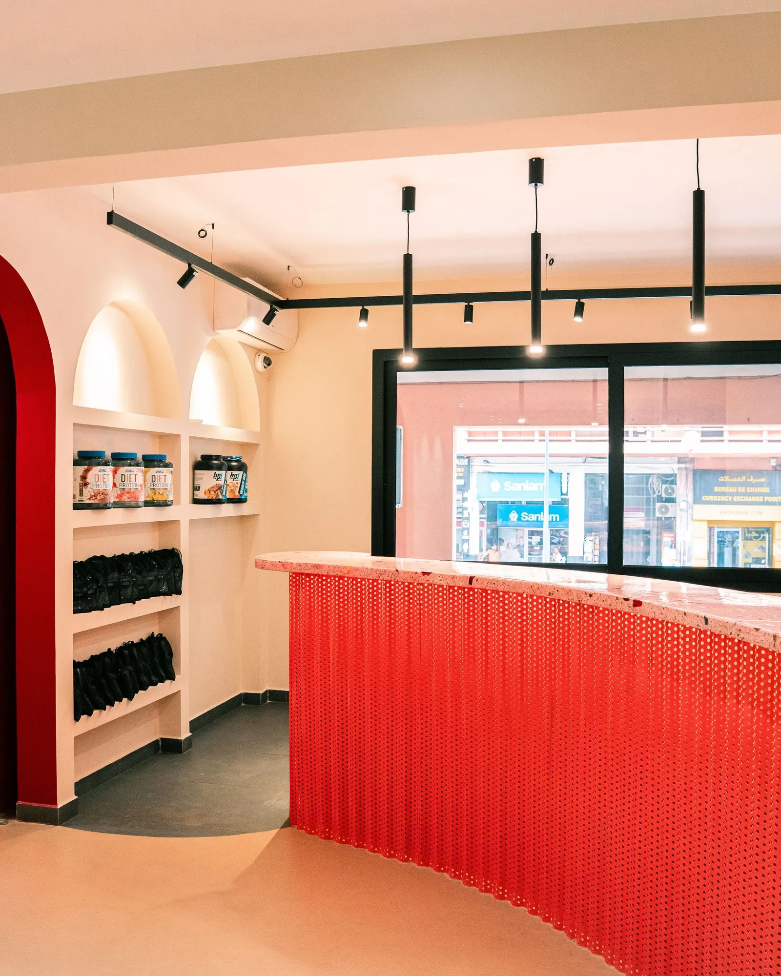 Le comptoir rouge perforé du café KURV et son arche laquée